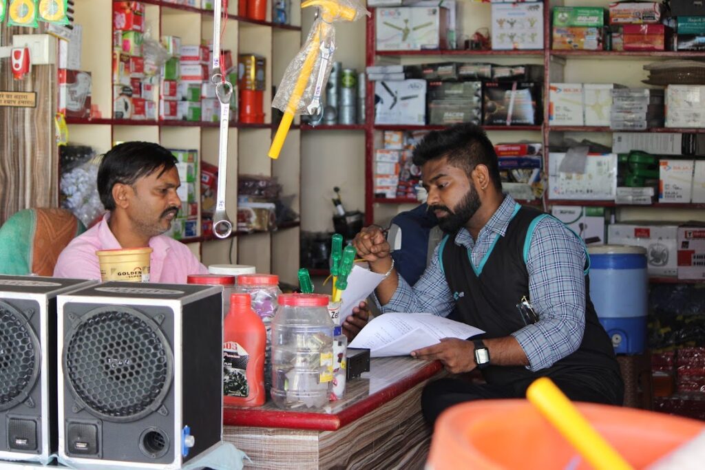 Anaxee field rep reviewing order form with local hardware shopkeeper amid stocked shelves