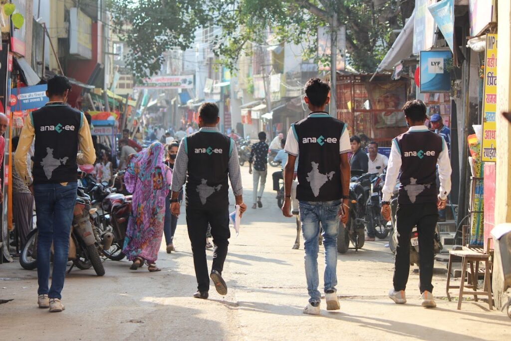 Four Anaxee Digital Runners in branded vests walk down busy market street to map retailers
