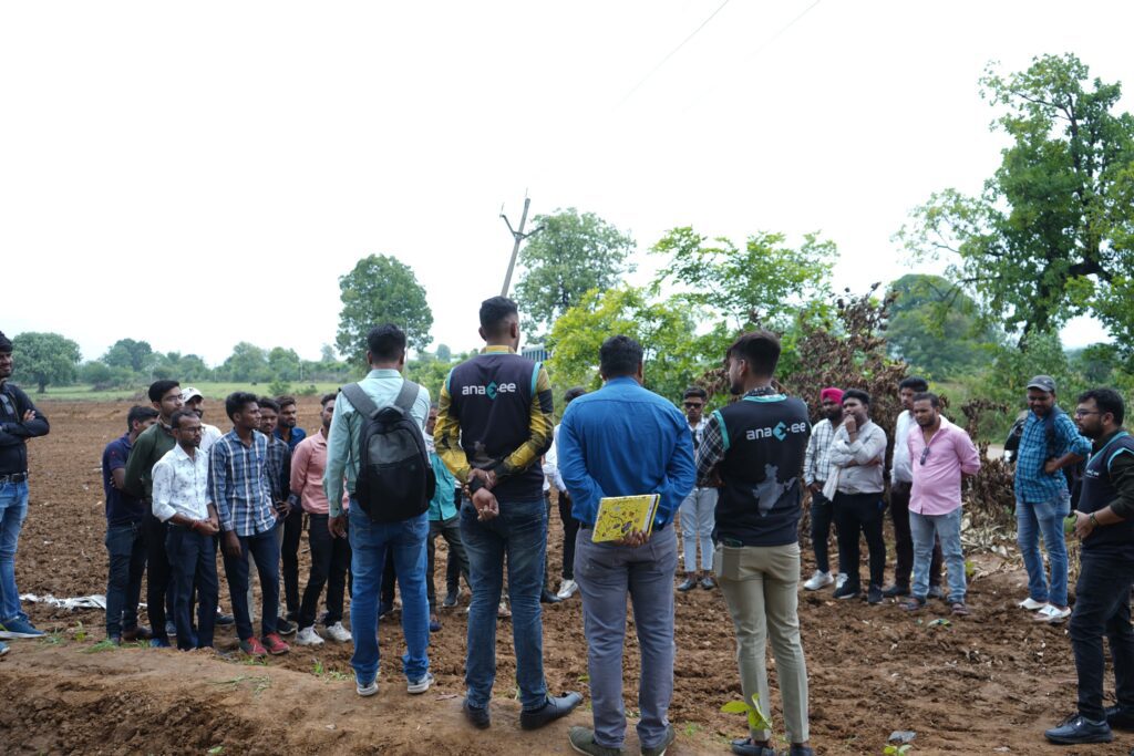 Anaxee field team members wearing branded vests engaging with a group of local community members in a rural setting as part of climate and carbon project awareness and training.